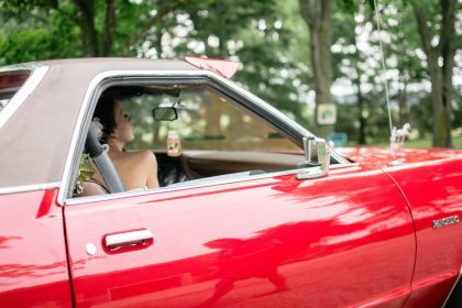 retro wedding theme bride sitting in a red vintage car