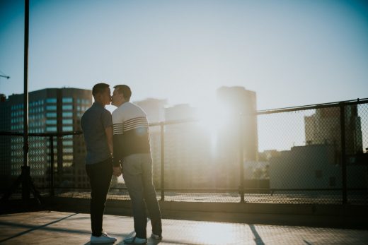 gay engaged couple pose kissing at sunset on top of building in downtown Los Angeles